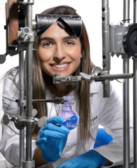 Dr. Hezebizadeh is shown wearing a white lab coat posing with scienitific instruments