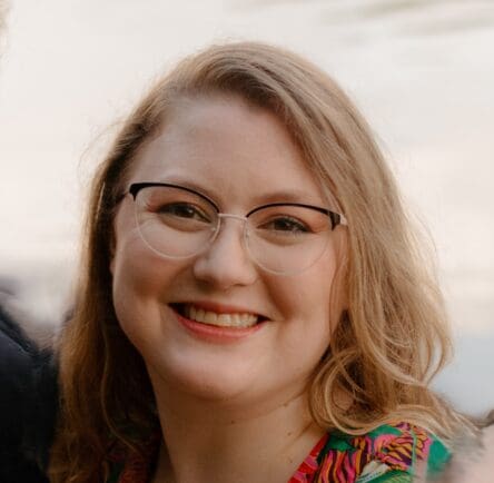 Dr. Rebekah white is shown wearing glasses, smiling, with her hair down