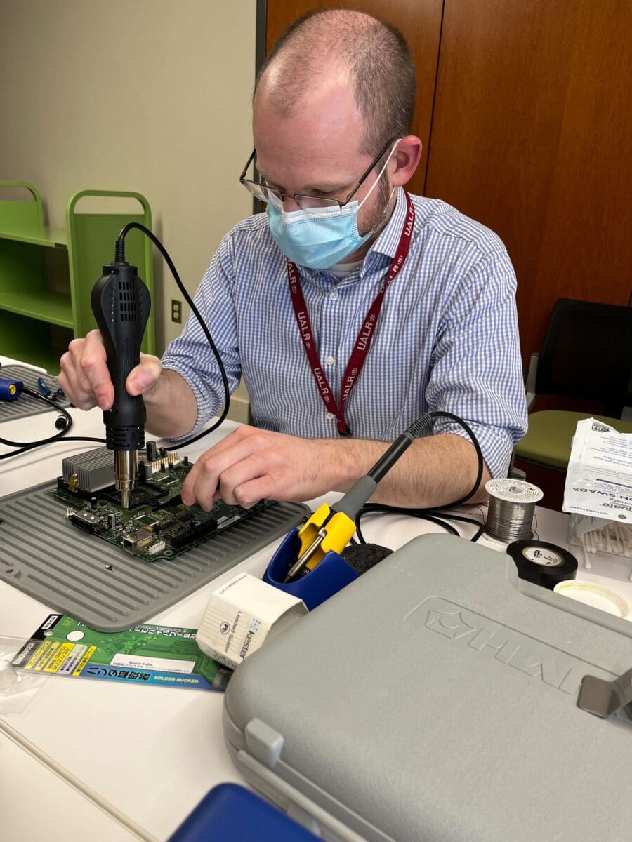 A graduate assistant welds a piece onto a computer board