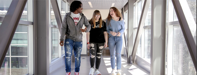 Three students walking and smiling.