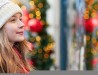 Young lady in knit snow hat with holiday decorations behind her.