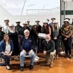 graduates posing with mentors for photo during topping out ceremony