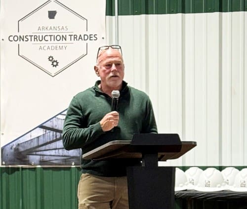 Hank Bray dept chair speaking at ceremony with Arkansas Construction Trades Academy sign in the background