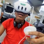 african american male youth interacts with virtual reality device wearing headset and using two hand held controllers