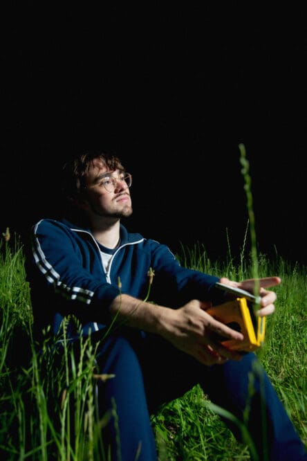 Young man sitting in grass at night