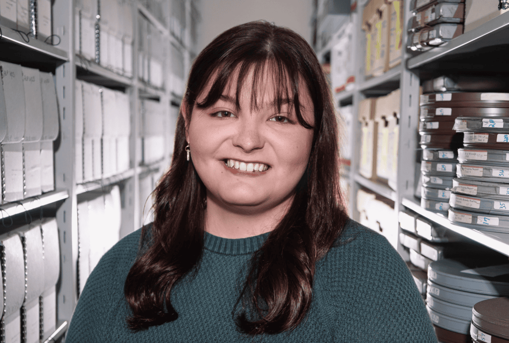 Headshot of Carlie Cowgill standing in front of archival boxes.