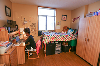 A student studying in her dorm room at her desk.