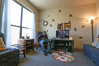 A student sits in the living room of a Commons Apartment.