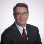 Headshot photo of CIO Brian Keltch dressed in dark siut, white shirt, burgundy tie.