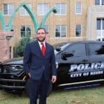 Beebe Police Chief Barron Dickson stands beside a Beebe police SUV outside the UA Little Rock William H. Bowen School of Law.