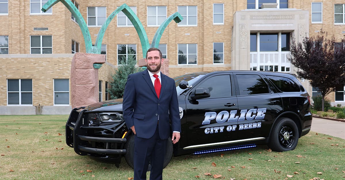Beebe Police Chief Barron Dickson stands beside a Beebe police SUV outside the UA Little Rock William H. Bowen School of Law.