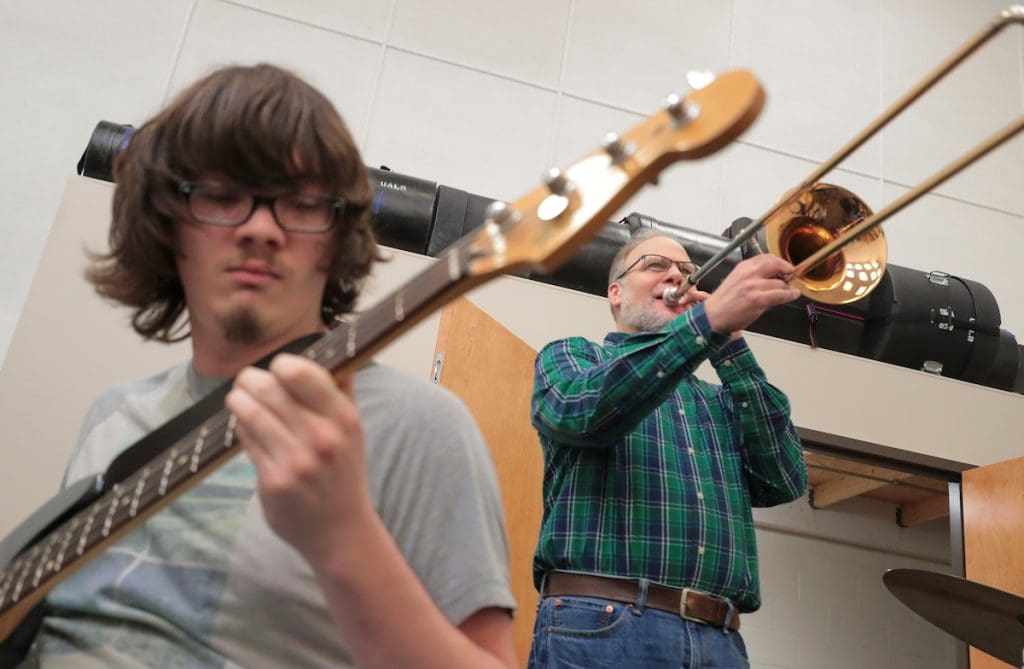 Jazz Ensemble student pictured playing guitar in foreground, Jazz Ensemble Director pictured playing trombone in background