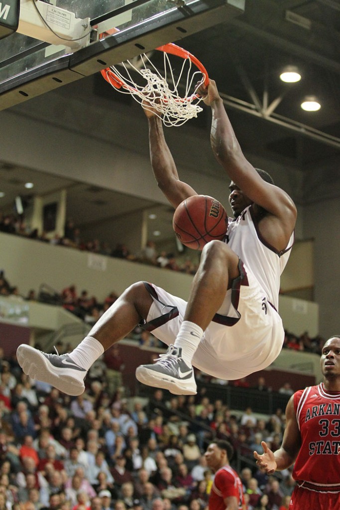 Little Rock Trojans player Roger Woods holds the rim after a slam dunk