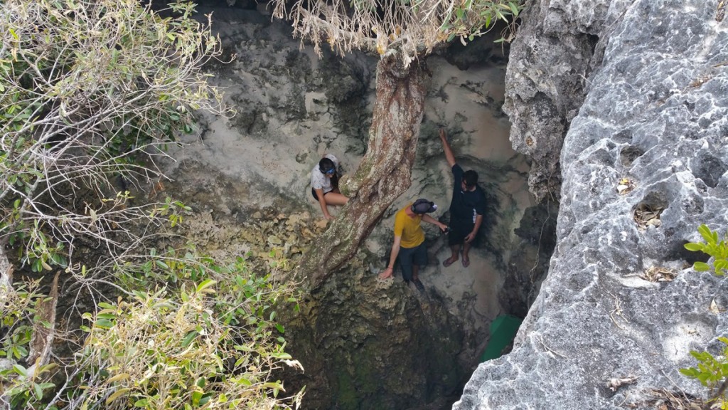 A photograph of three students exploring a cave. 