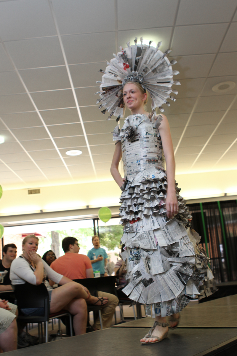 Student poses on catwalk, showing off her newspaper dress.