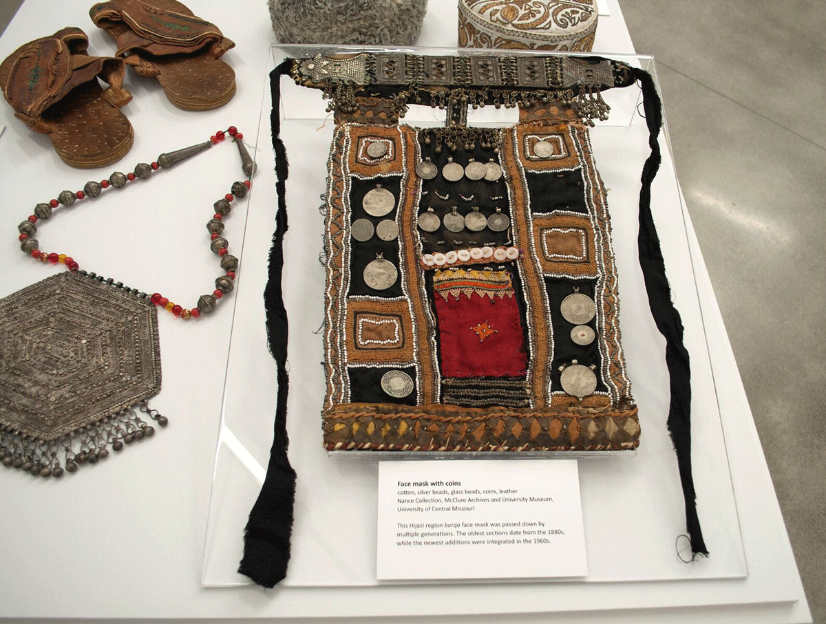 A face mask with cotton, silver beads, glass beads, coins, and leather is shown from the "Traditional Arts of the Bedouin" exhibition.