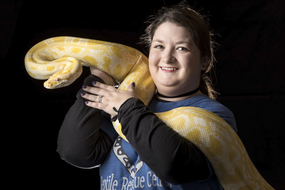 Janna Shepherd holds one a rescued albino burmese python that lives at the Reptile Rescue Center.