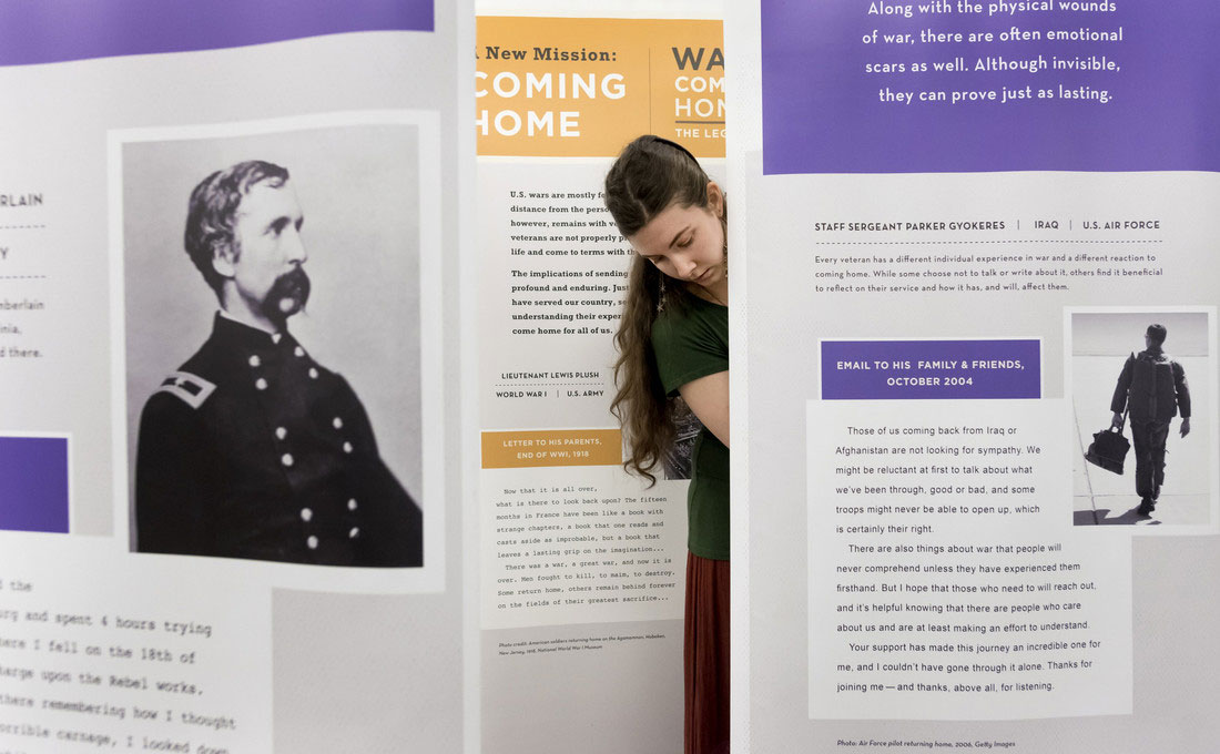 Chelsea Young setups the War Comes Home exhibit at the Ottenheimer Library .