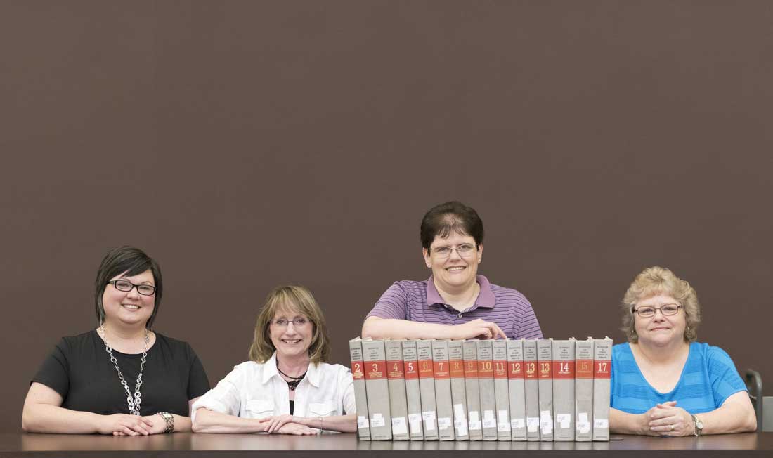 Erin Fehr, Donna Rose, Karen Russ, and Carol Macheak hold volumes of “The Handbook of North American Indians,” the historic publication Ottenheimer Library has agreed to preserve.