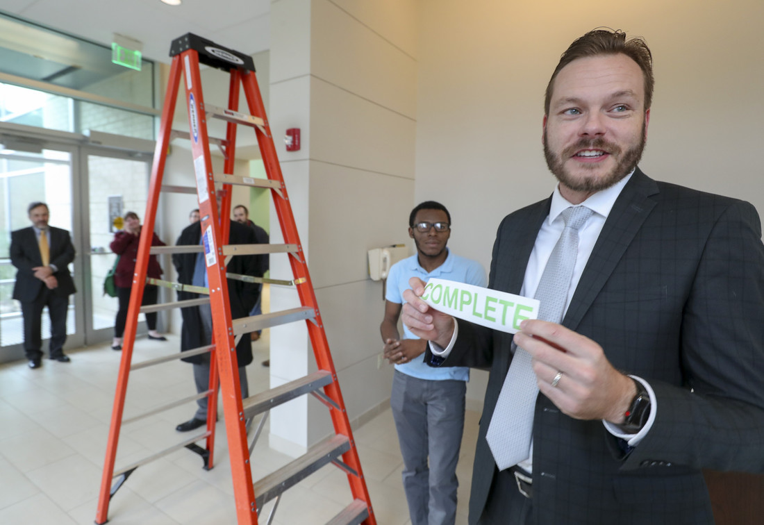 Thomas Bunton, UA Little Rock director of Technology Infrastructure and Operations, holds a sign marking the completion of a campus wide networking system upgrade after installing the last piece of equipment in the Center for Integrative Nanotechnology Sciences. Photo by Ben Krain