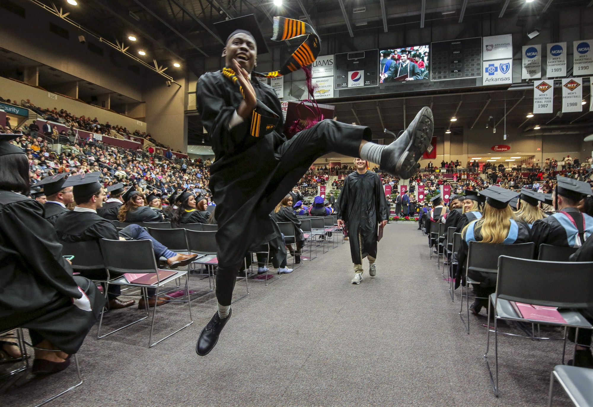 A UA Little Rock student leaps in the air to celebrate his graduation in December 2018.
