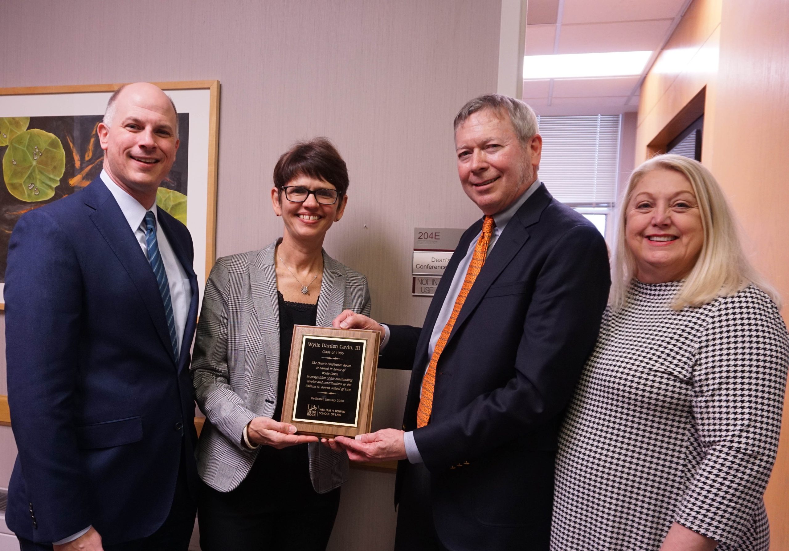 Bowen Dean Theresa Beiner (center left) presents alum Wylie Cavin III (center right) with a plague naming the Dean's Conference Room in his honor. Also pictured are Christian O'Neal (left), vice chancellor for university advancement, and Wanda Hoover (right), Bowen's assistant dean of external relations. Photo by Tina Medlock.