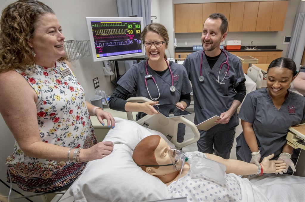 Nursing school students working with medical equipment in the SIM Lab, SIM Lab control room and Pixus units.