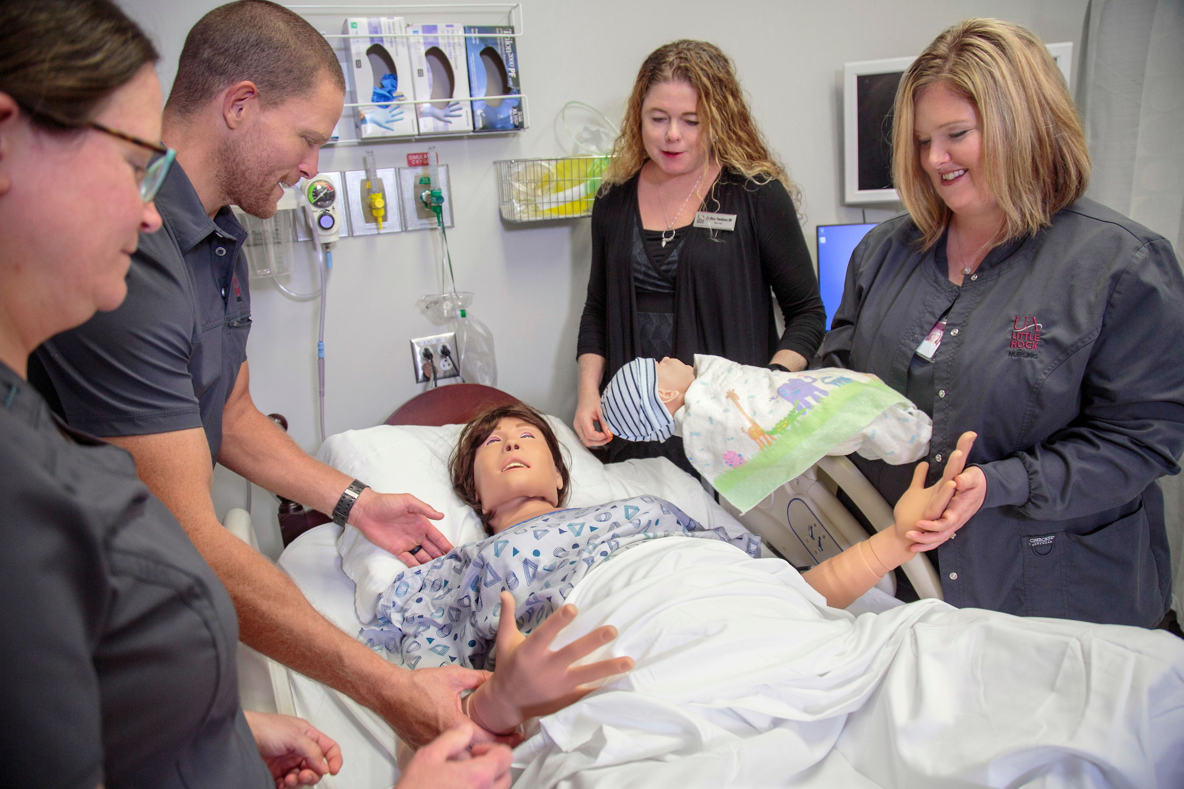 Dr. Sloan Davidson, director of the UA Little Rock School of Nursing, leads a group of nursing students who are training with the birthing manikin simulator in the UA Little Rock Center for Simulation Innovation. Photo by Ben Krain.