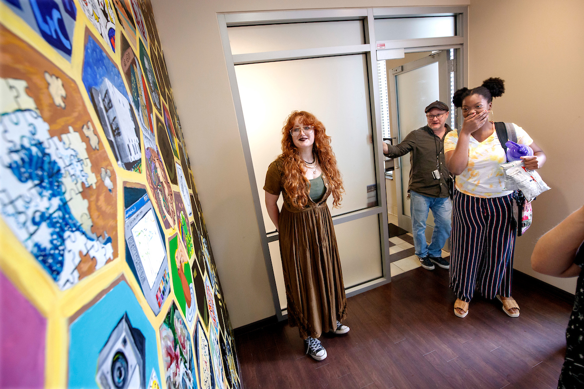 A student living in West Hall reacts to a mural painted by art students in the hallway of her dorm. Photo by Ben Krain.