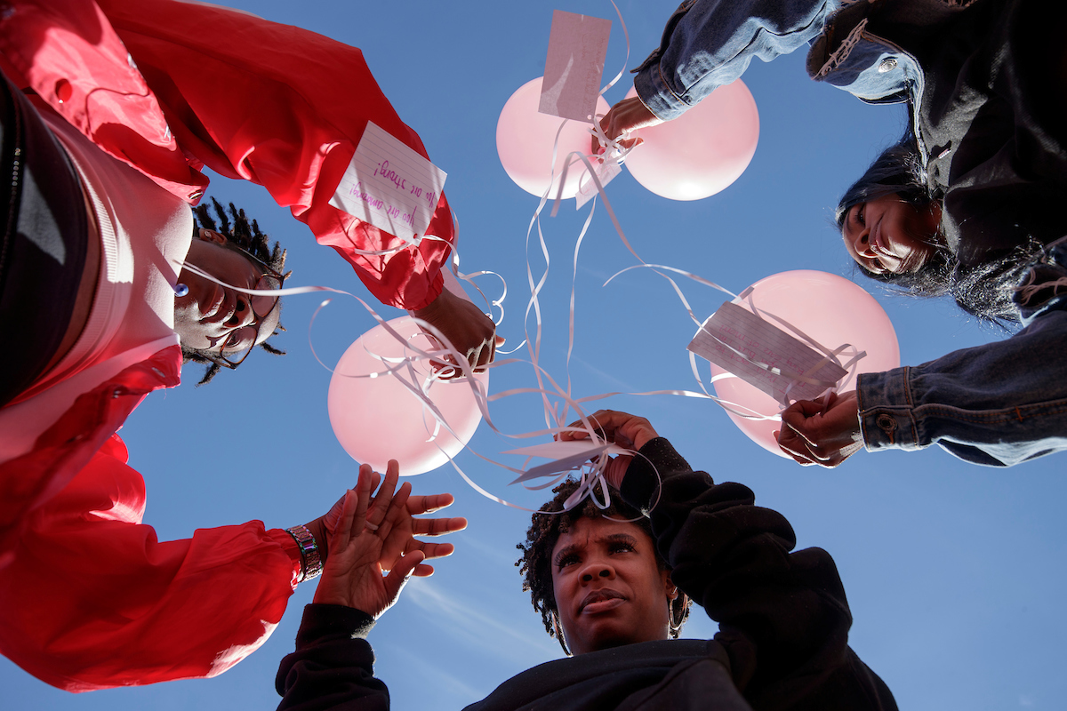 Students participating in Love Goes Pink Balloon Release write personal notes on their balloons celebrating breast cancer survivors and honoring those who died.