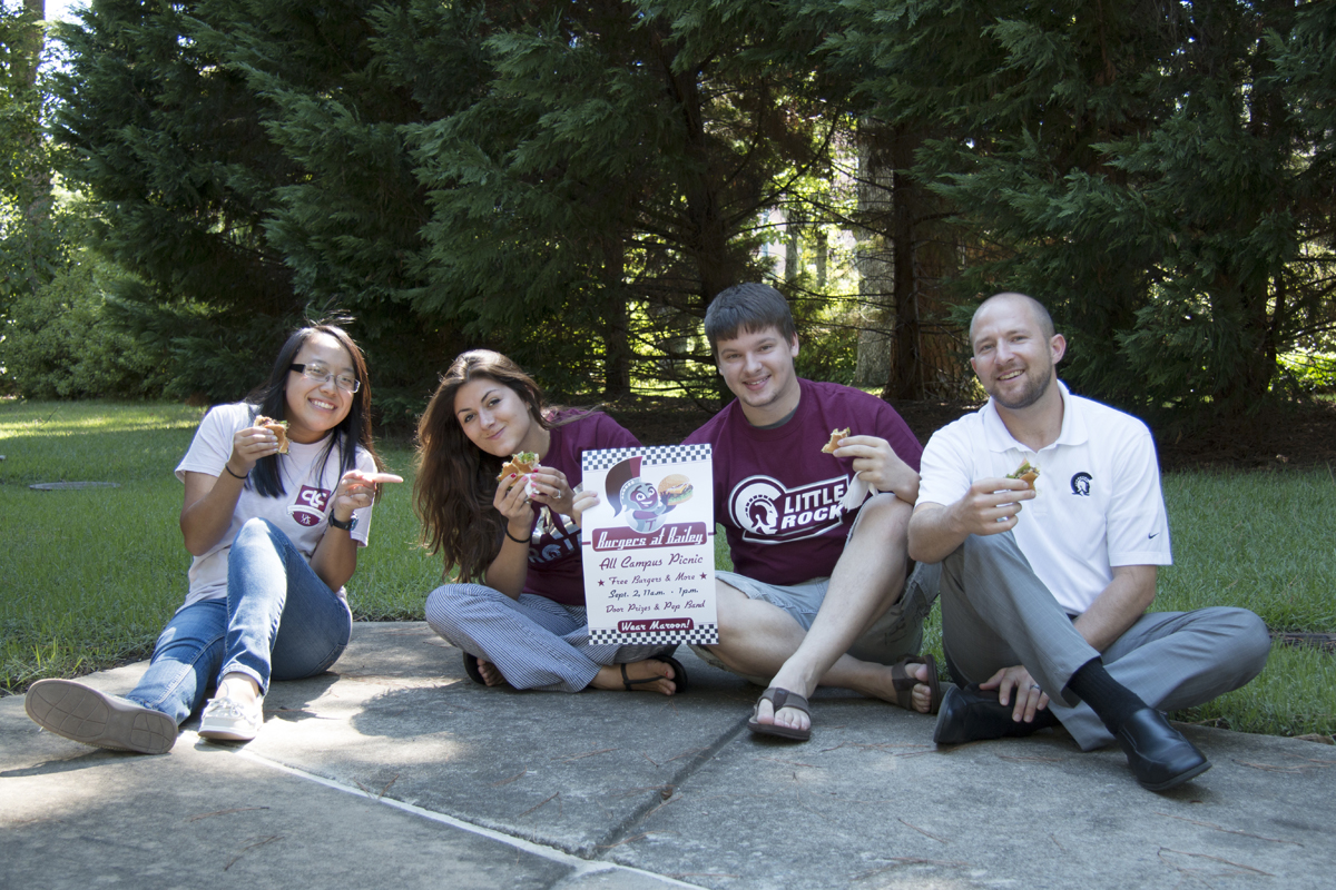 Students sit in the shade while eating hamburgers