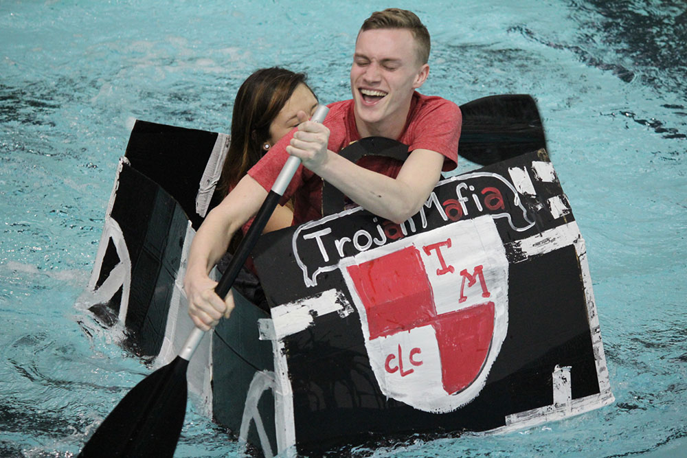 Participants in a past homecoming cardboard boat race strain to move the boat forward