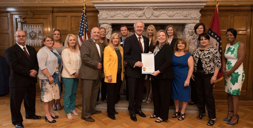 Gov. Asa Hutchinson signs a proclamation declaring May 16-20 as Certified Public Manager Recognition Week in the state of Arkansas. Pictured in the front row, from left to right, are: Don Childers, Barbara Mahoney, Nan Harrell, Rick Ward-Harder, Becky Bryant, Gov. Asa Hutchinson, Jolie Busby, Cynthia Nixon, Sharon Hacker, and Gaye Jones-Washington. Pictured in the back row, from left to right, are: Cleta Hardy, Lori Morrison, Chris Colclasure, Rebecca Edwards, Nikki Heck, and Anna Swaim.