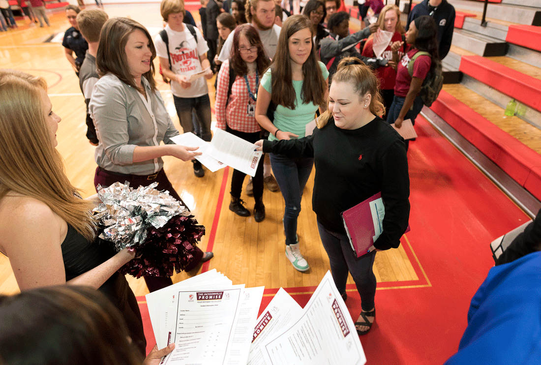 UALR recruiter Whitney Calliote hands out information to Jacksonville High School student Cassidy Smith about a new early-commitment program with that will give students a more affordable college education and a guaranteed seat in college.