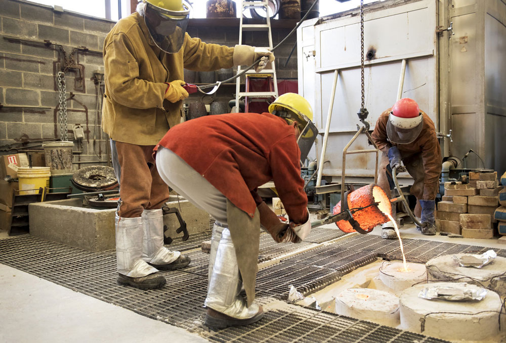 Patrick Fleming (left), Marianne Hedinger (center), and Michael Warrick (right) pour bronze for the sculpture, "Youth," which will be given to Hanam City as part of a sculpture exchange between Hanam City and Little Rock. Photos by Lonnie Timmons III/UA Little Rock Communications.