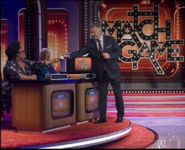 Cheryl Humphrey (left) hands Match Game Host Alec Baldwin (right) a sample of Candy Butta. Photo from Cheryl Humphrey.