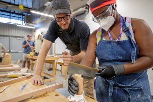 Woodworking Professor Peter Scheidt assists visiting art educator Loni Rainey as she builds a small Shaker table during the artWAYS furniture and woodworking program in the Windgate Center of Art and Design. Photo by Ben Krain.