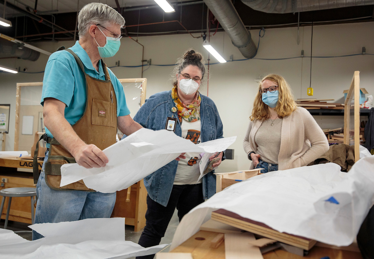 Historic Arkansas Museum curators Victoria Chandler and Carey Voss look over a student's woodworking design plan as he prepares for an upcoming HAM exhibit "Dovetails/We Fit Together".