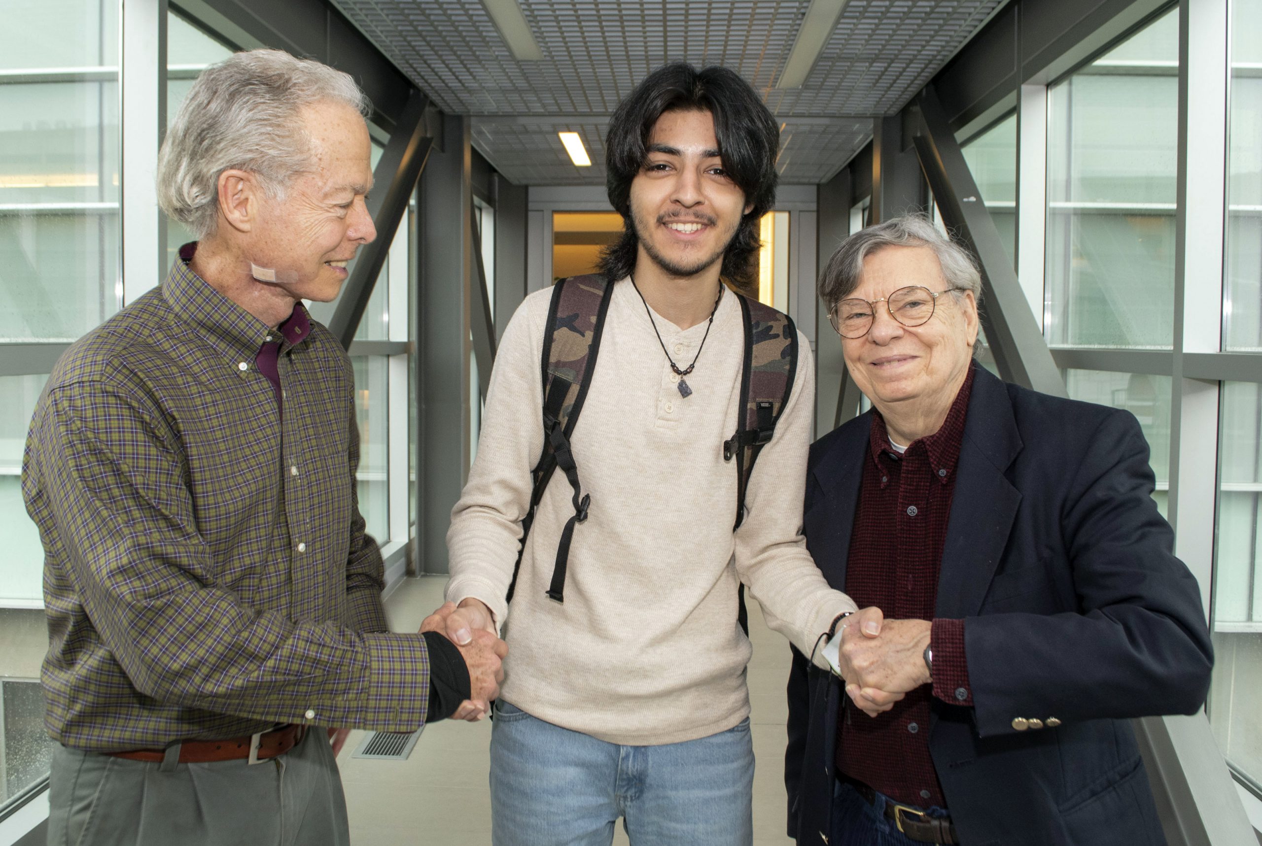 UA Little Rock student Luis Martinez, center, shakes hands with Dr. Terry Trevino-Richard, left, and Dr. Andre Guerrero, right.