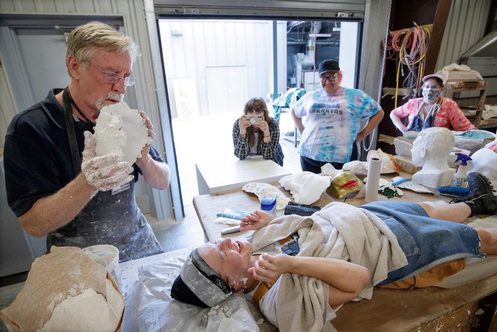 UA Little Rock Professor Michael Warrick, left, removes a plaster face mold from a participant during a demonstration to art educators. The group was part of the summer 2022 artWAYS art teachers workshop.