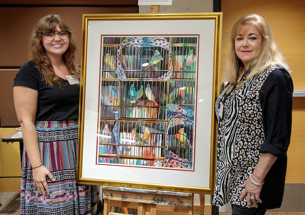 Scholarship recipient Annika Wade, left, and scholarship donor Leslye Shellam, right, are shown with a painting Shellam donated to UA Little Rock that was painted by her mother, Linda Blaine Flake. Photo by Ben Krain.