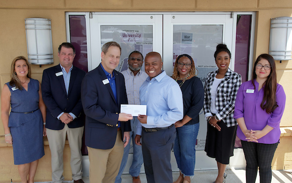 Barrett Allen and members of the University District receive a donation from members of Cadence Bank.