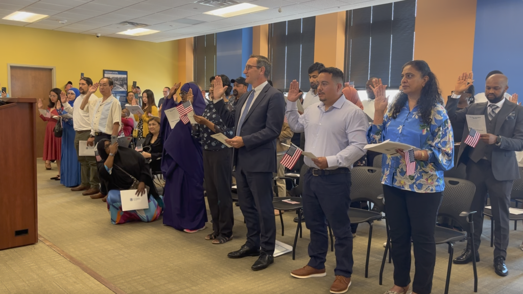 Professor Julien Mirivel takes the citizenship oath with other new U.S. citizens in Memphis, Tennessee.