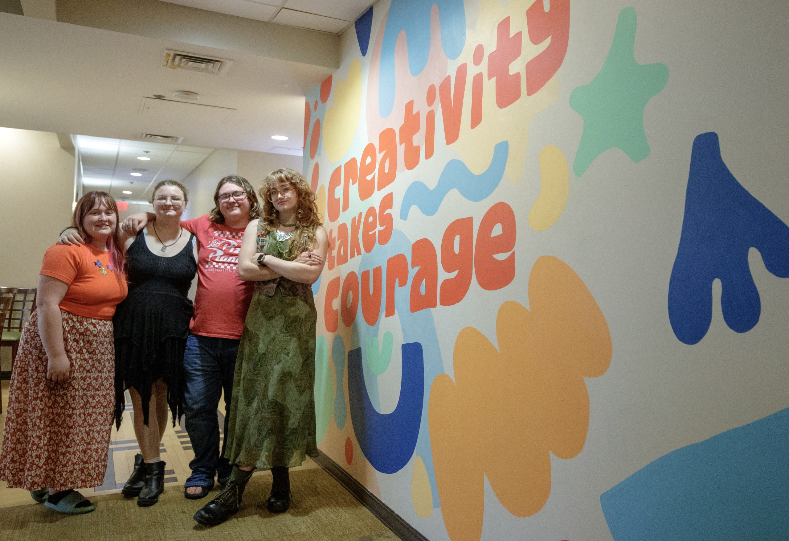 Art students show off an inspirational mural they painted in the West Hall. Photo by Ren Miller.