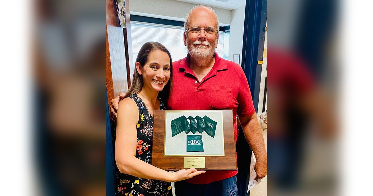 Klanzee Tozer and Bill Buddenberg hold the In-Print 2024 Gold Award from the In-Plant Printing and Mailing Association.