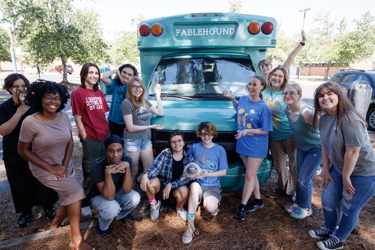 Thirteen students stand in front of a blue school bus with "Fablehound" written across the top.