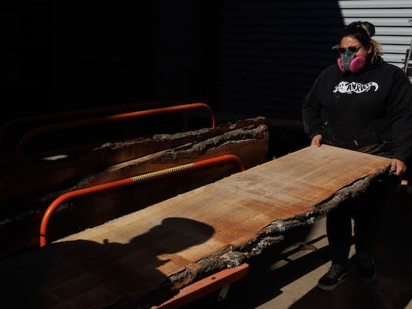 Kim Arcega operate a mill saw to cut wood for tables for a new student lounge at UA Little Rock. Photo by Benjamin Krain.