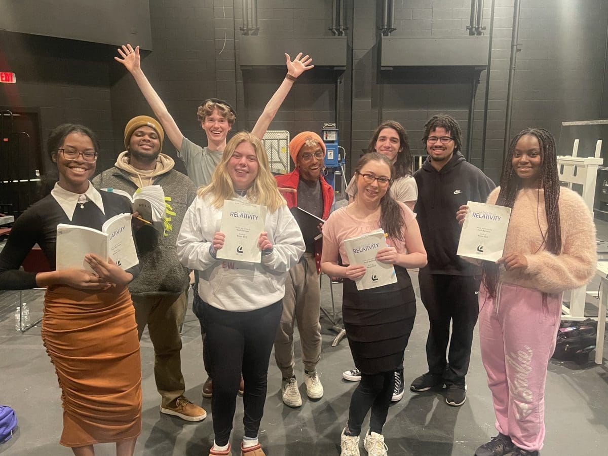 Nine students pose with "The Theory of Relativity" scripts.