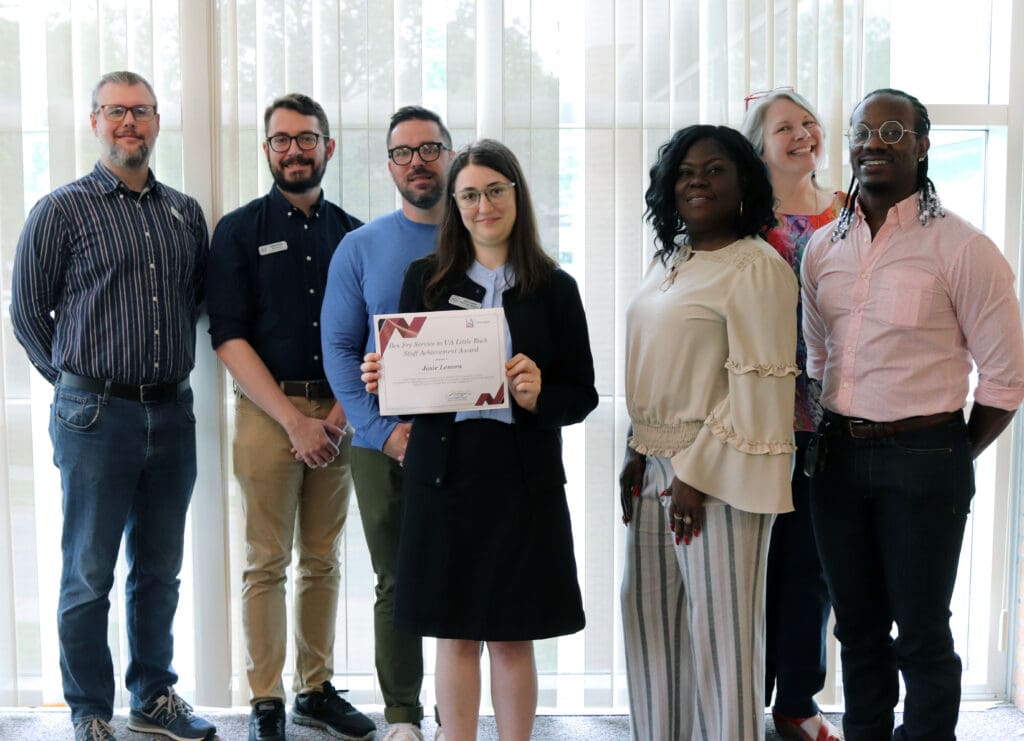 Josie Lenora, center, receives the Ben Fry Service to UA Little Rock Award surrounded by her co-workers at Little Rock Public Radio.