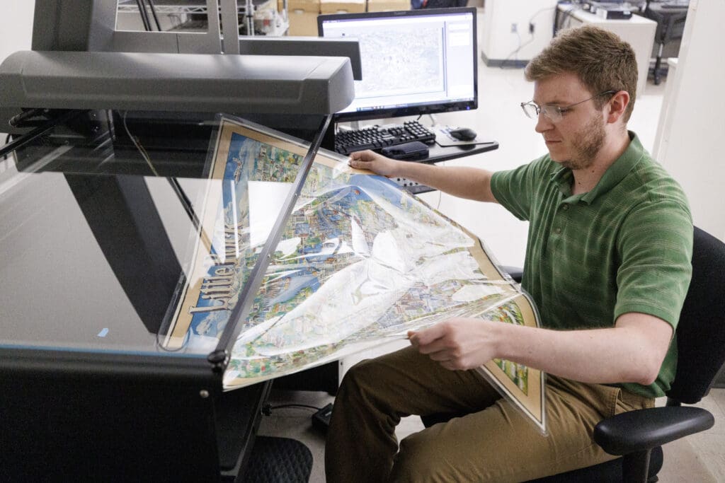 Cole Hadden, a recent history graduate, scans maps at the Center for Arkansas History and Culture while working on the map digitization project.  Photo by Benjamin Krain.